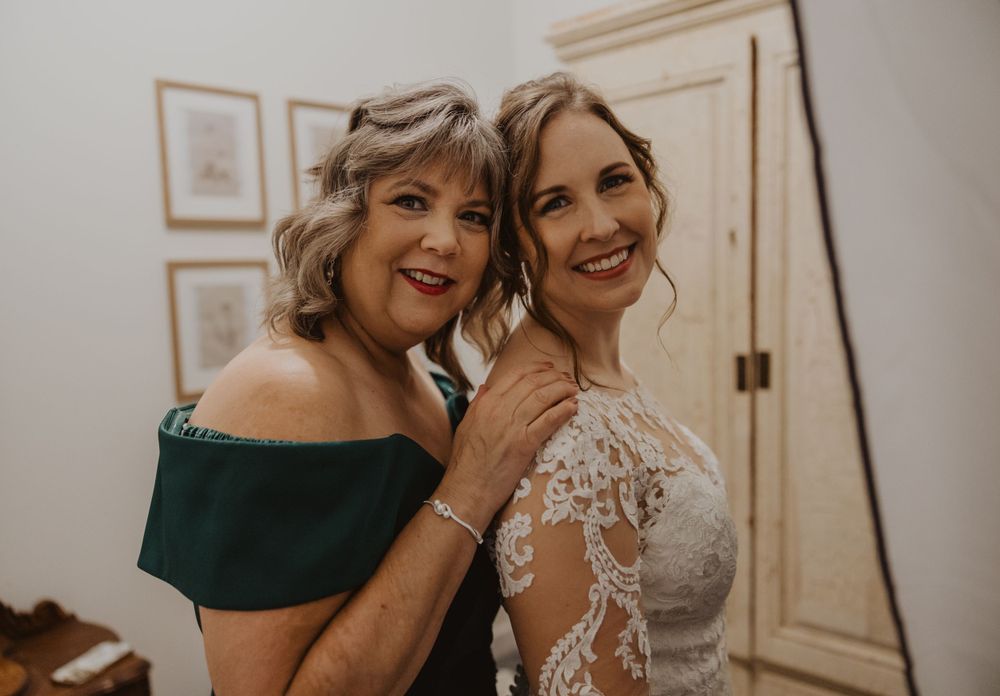 Emotional wedding preparation moment with elegant white lace dress details.