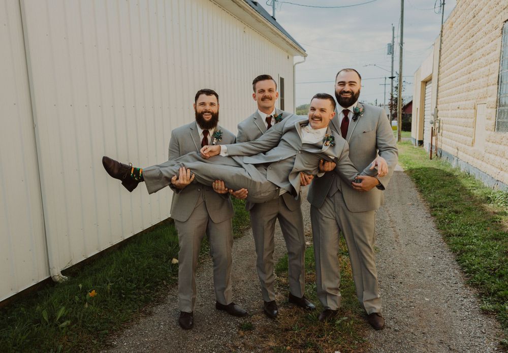 Wedding party members execute coordinated dance moves in their gray suits.