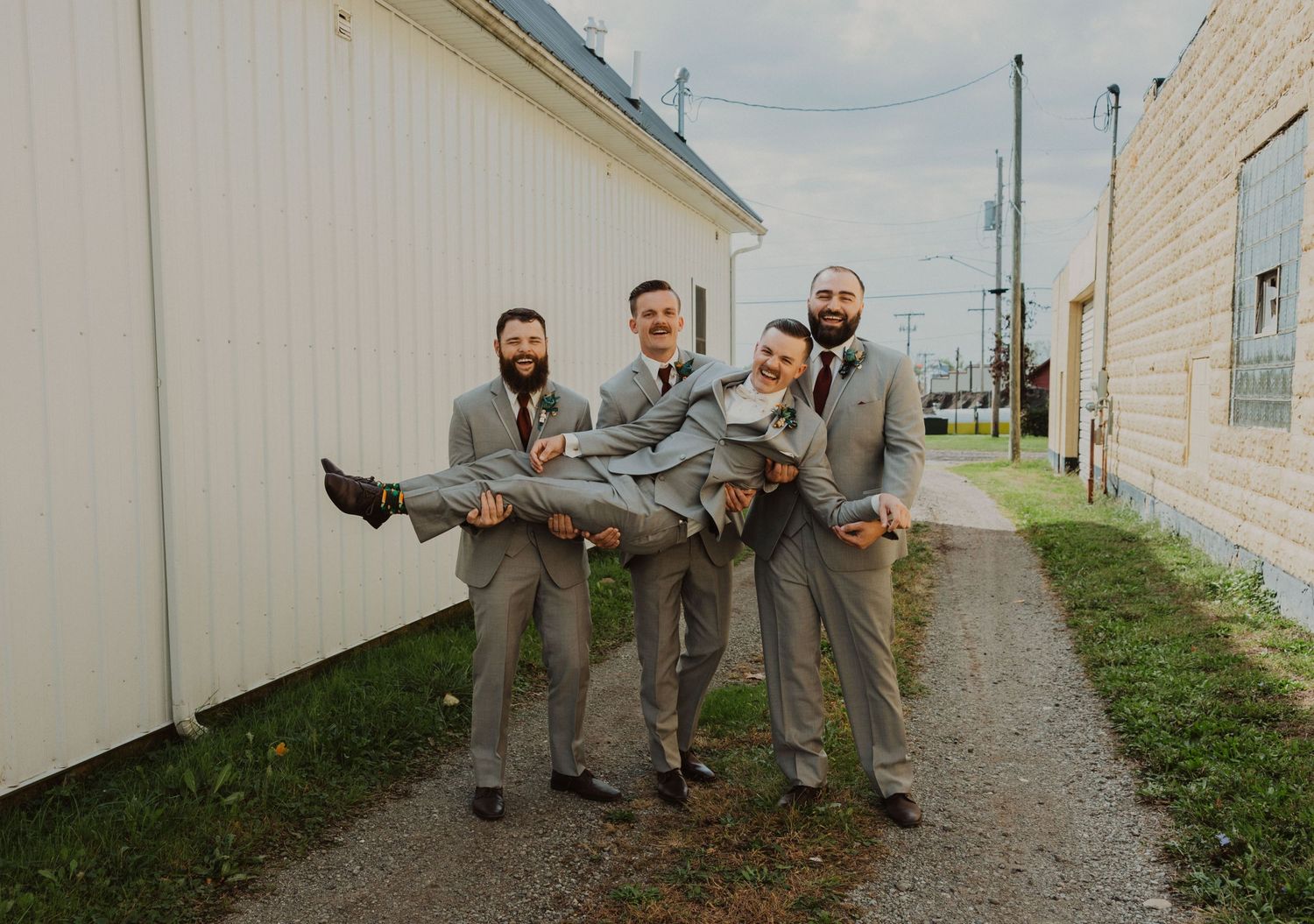 Groomsmen in matching attire perform synchronized poses during outdoor photo session.