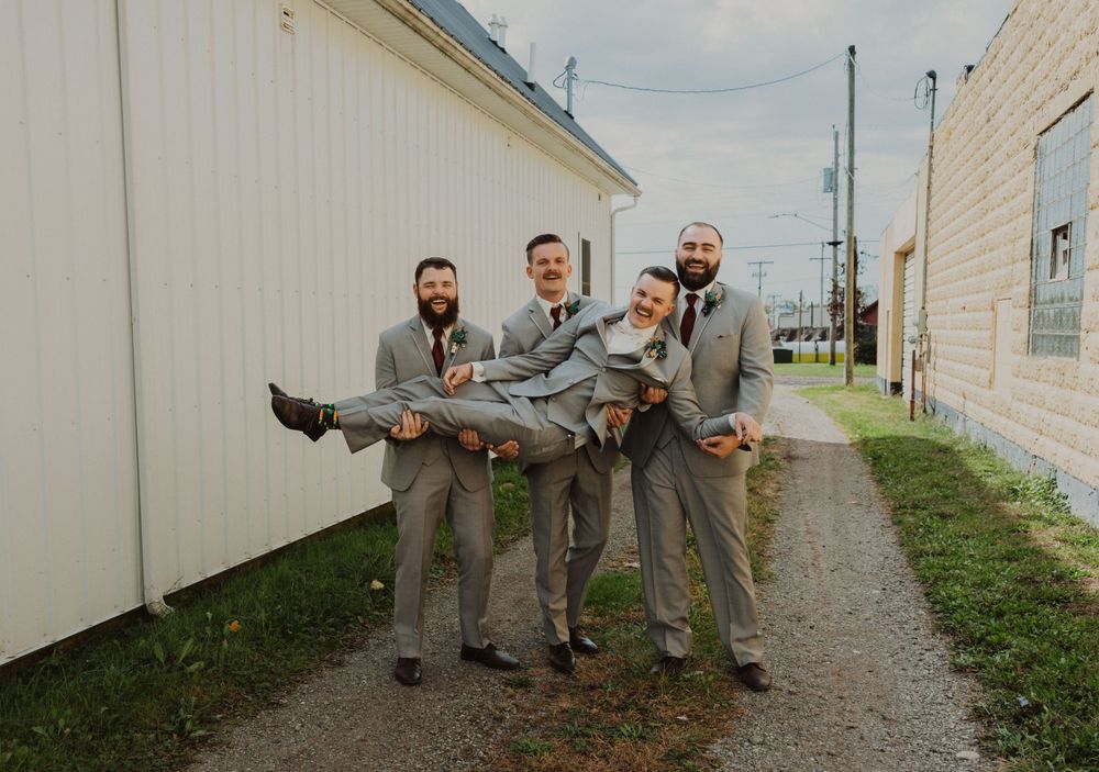 Groomsmen in matching attire perform synchronized poses during outdoor photo session.