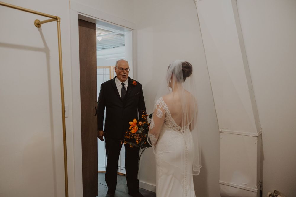 A series of emotional first look photos between the bride and her father in a white corridor.