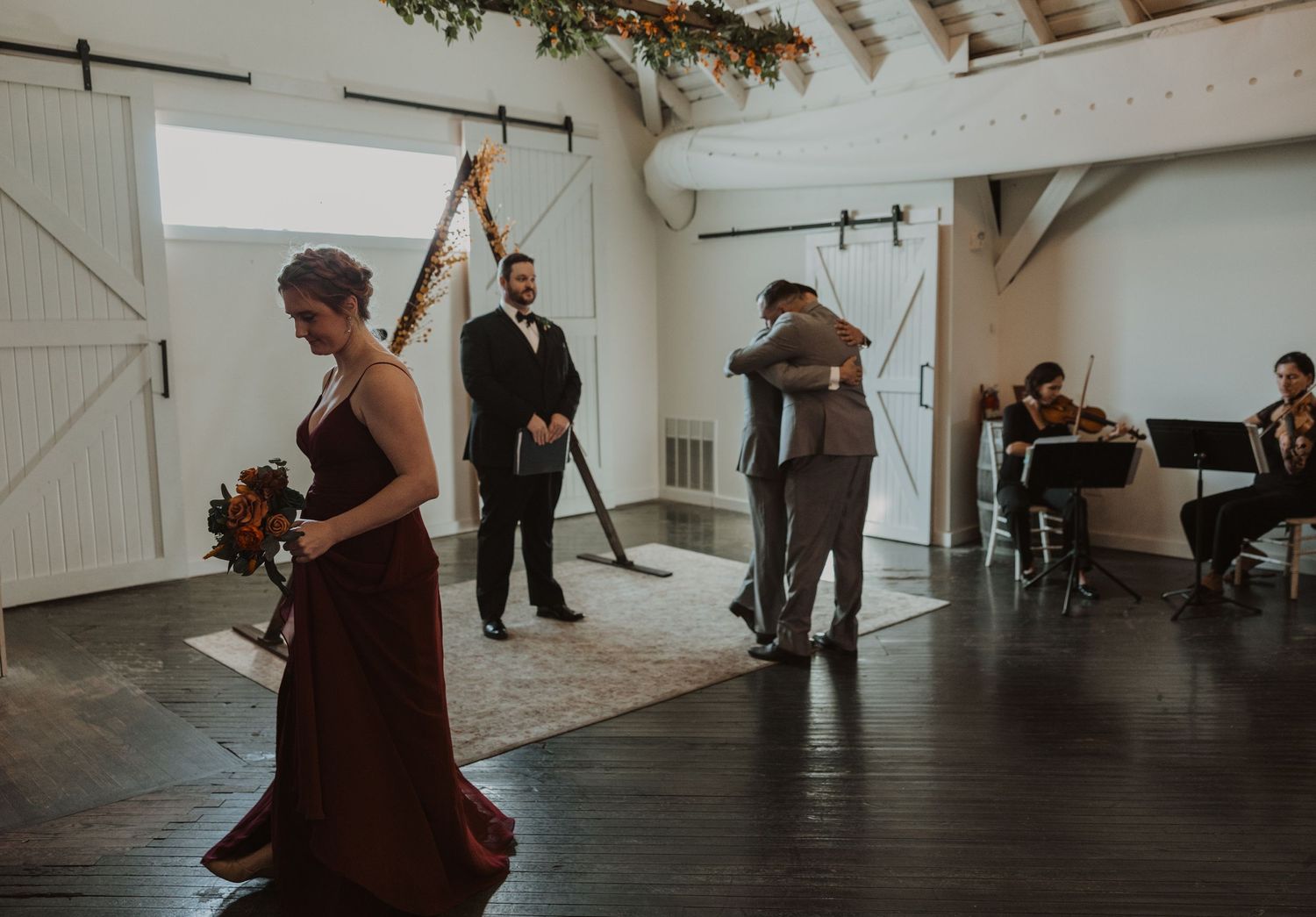 Wedding ceremony space with dark hardwood floors and white vaulted ceilings.