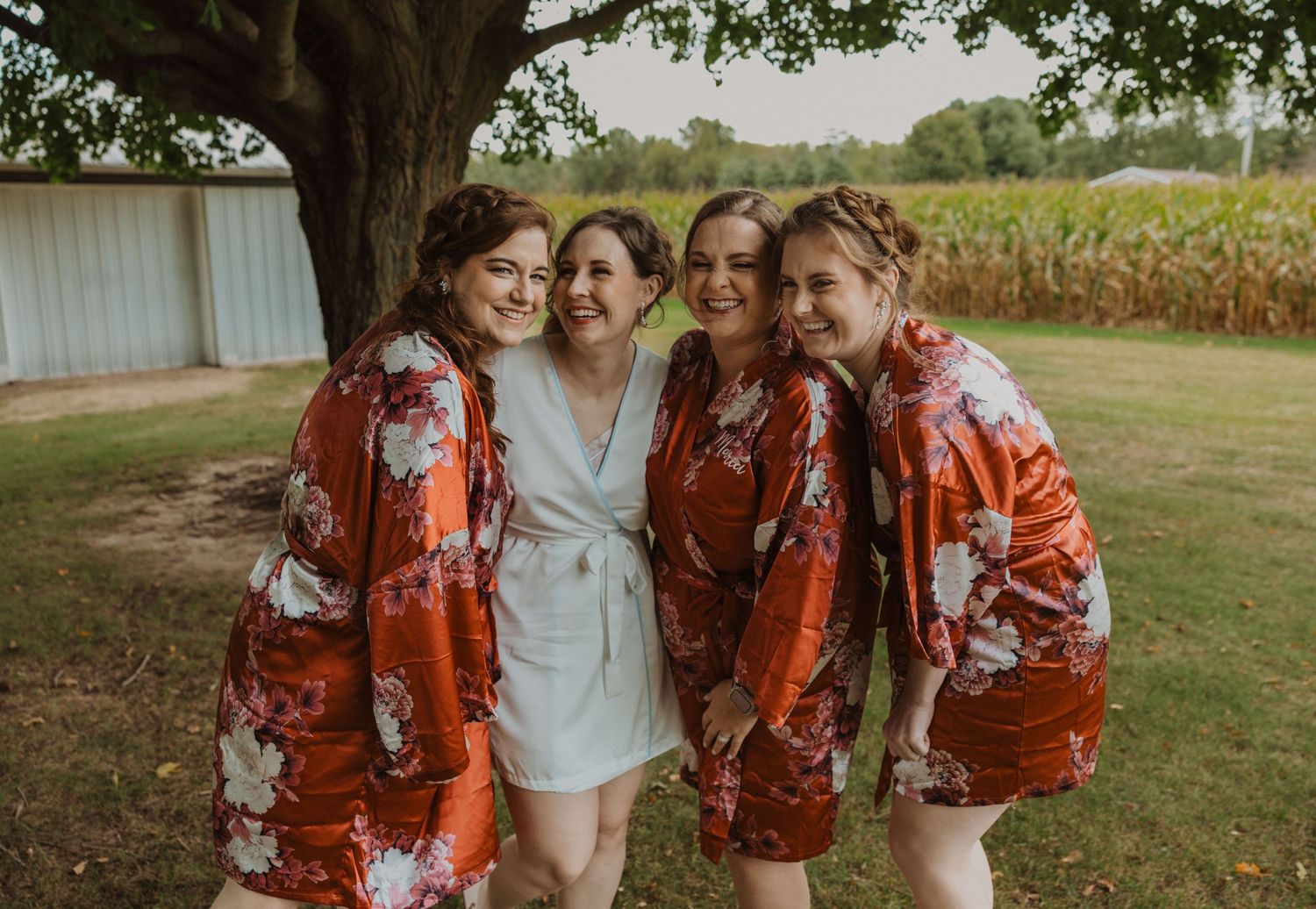Wedding party in red floral dresses poses together outdoors.