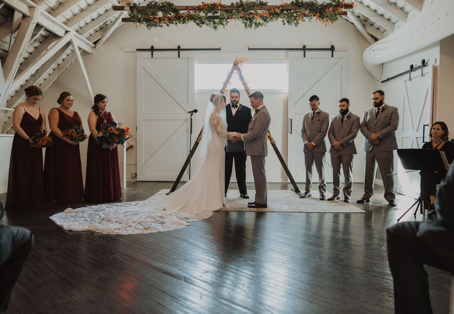 Elegant barn wedding venue with exposed beams and floral garland decorations on the ceiling.