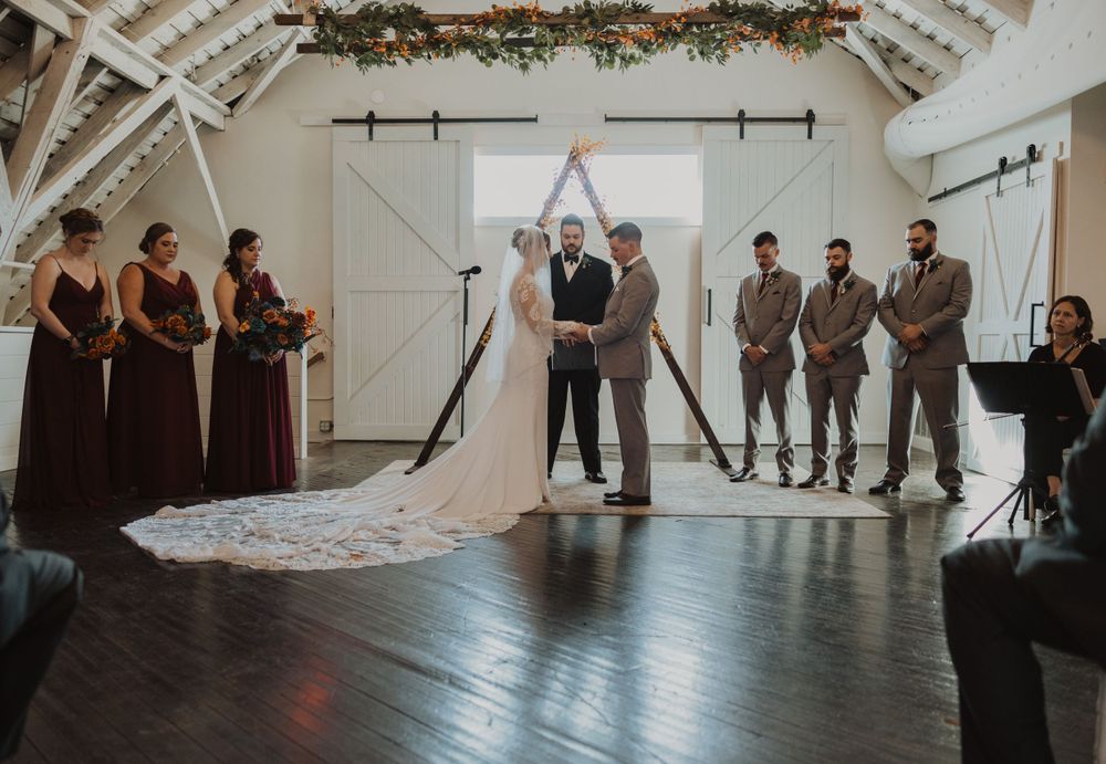 Elegant barn wedding venue with exposed beams and floral garland decorations on the ceiling.