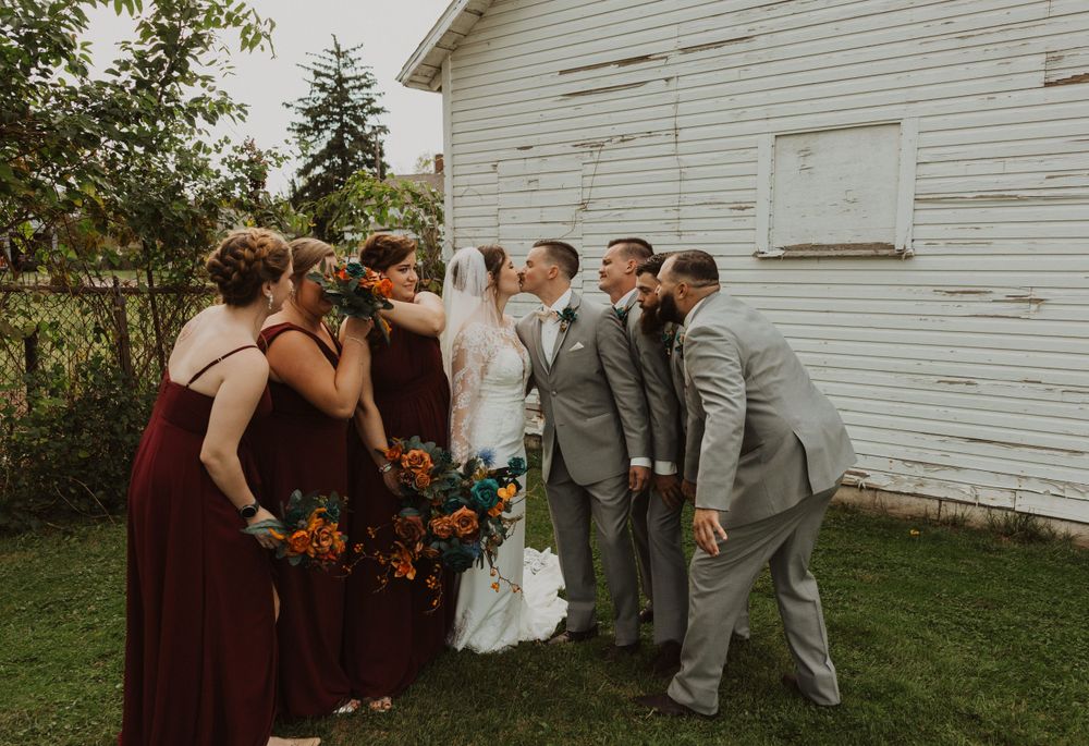 Wedding group creates relaxed moments against rustic barn backdrop.