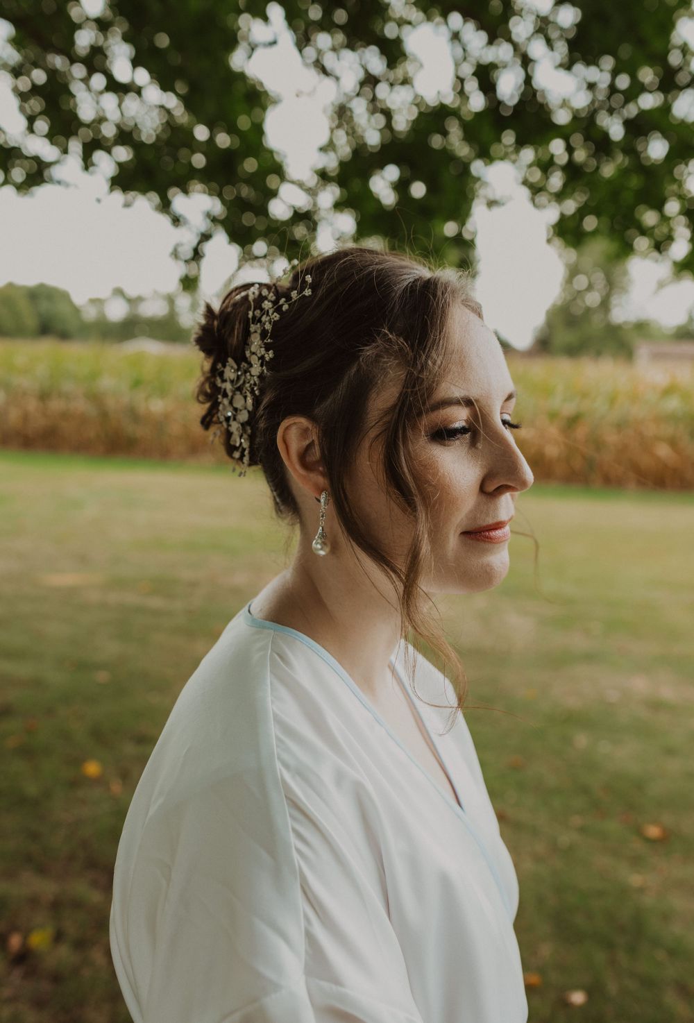 Bridal portrait with delicate hair accessories against natural bokeh background.