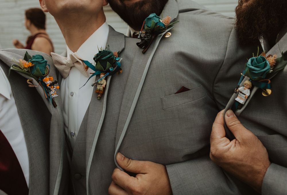 Wedding party members hold small decorative items while posing in their gray suits.