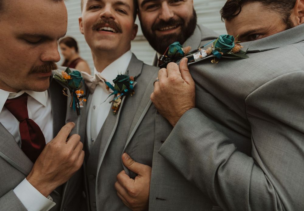 Groomsmen share candid laughs during informal wedding photo session.