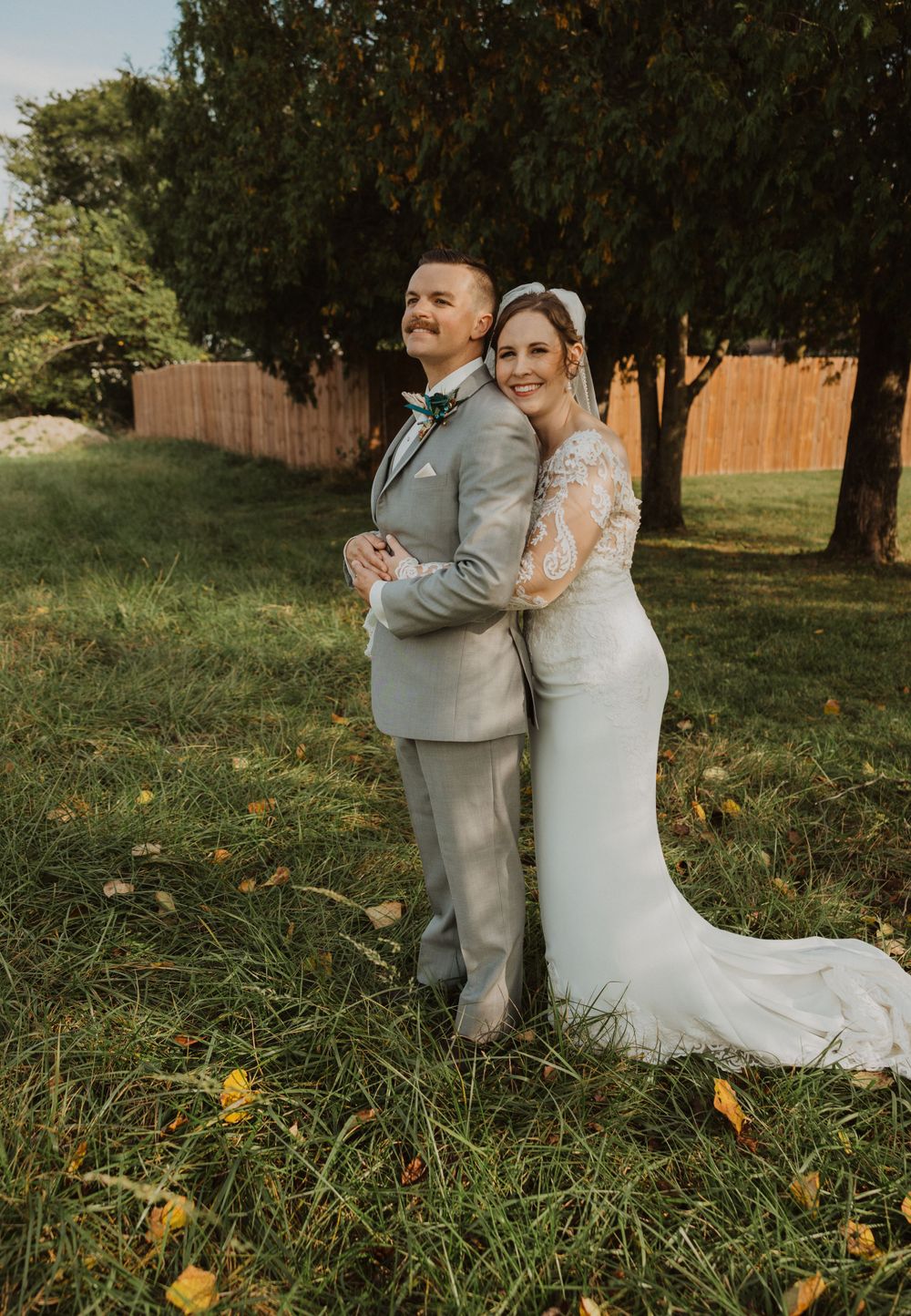 Elegant wedding portraits captured in field with autumn colors and natural lighting.