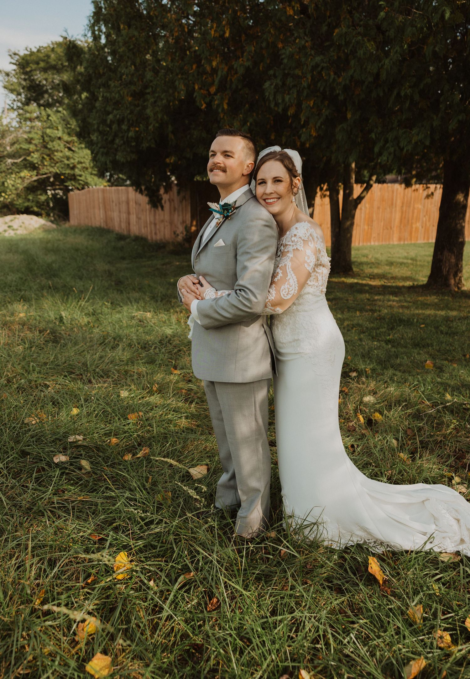 Elegant wedding portraits captured in field with autumn colors and natural lighting.
