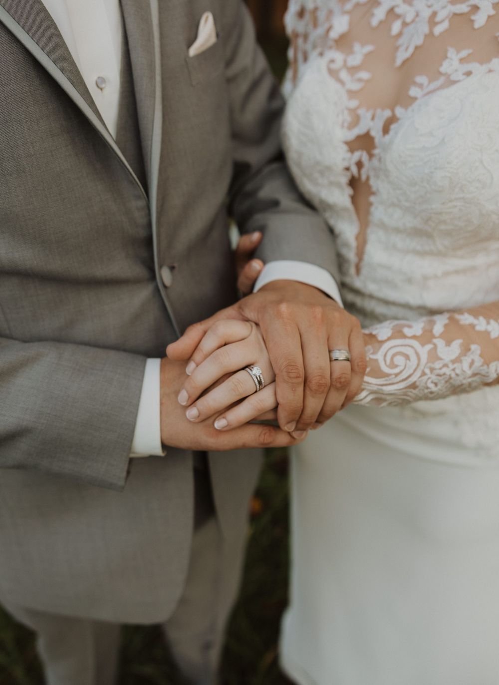 Close-up detail shot of wedding rings and lace dress details during an intimate moment.