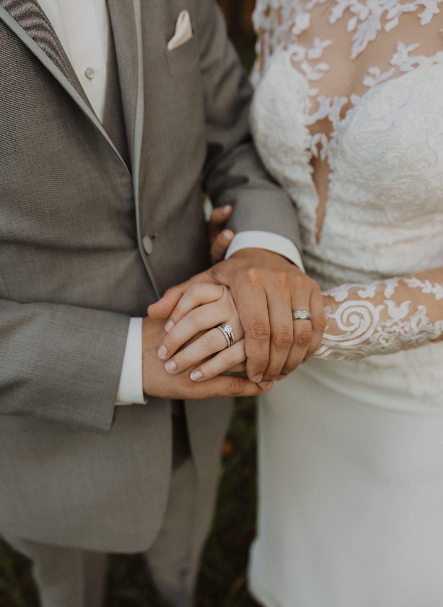 Close-up detail shot of wedding rings and lace dress details during an intimate moment.
