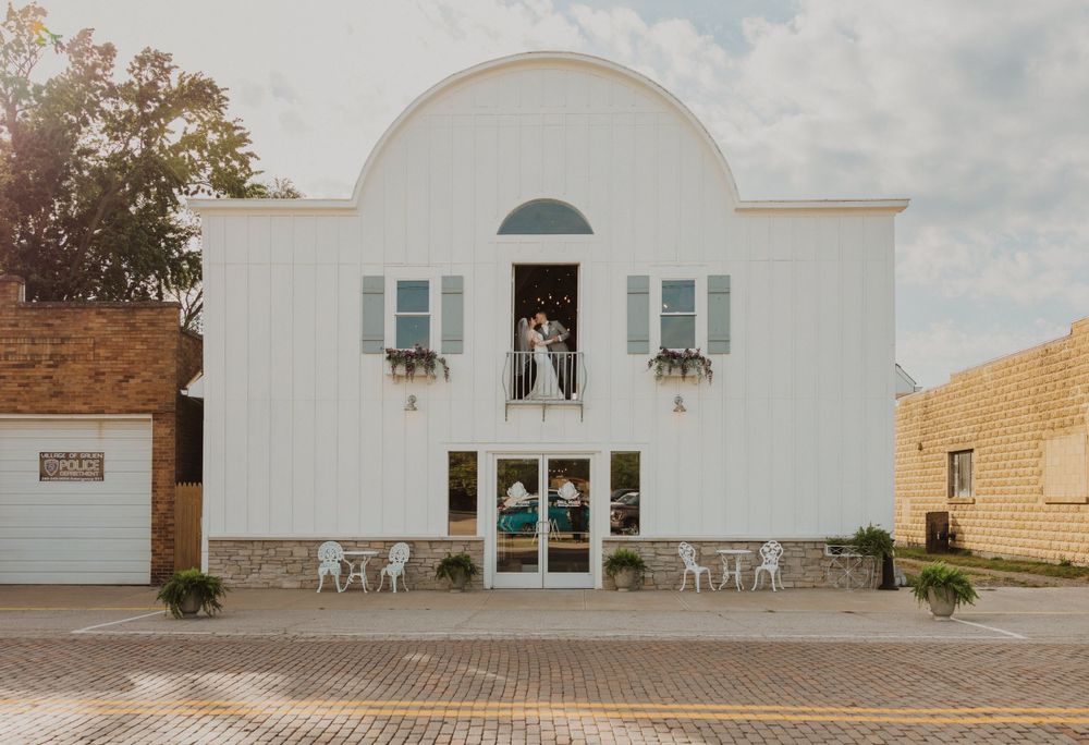 Contemporary white building facade with arched entrance and symmetrical window placement.