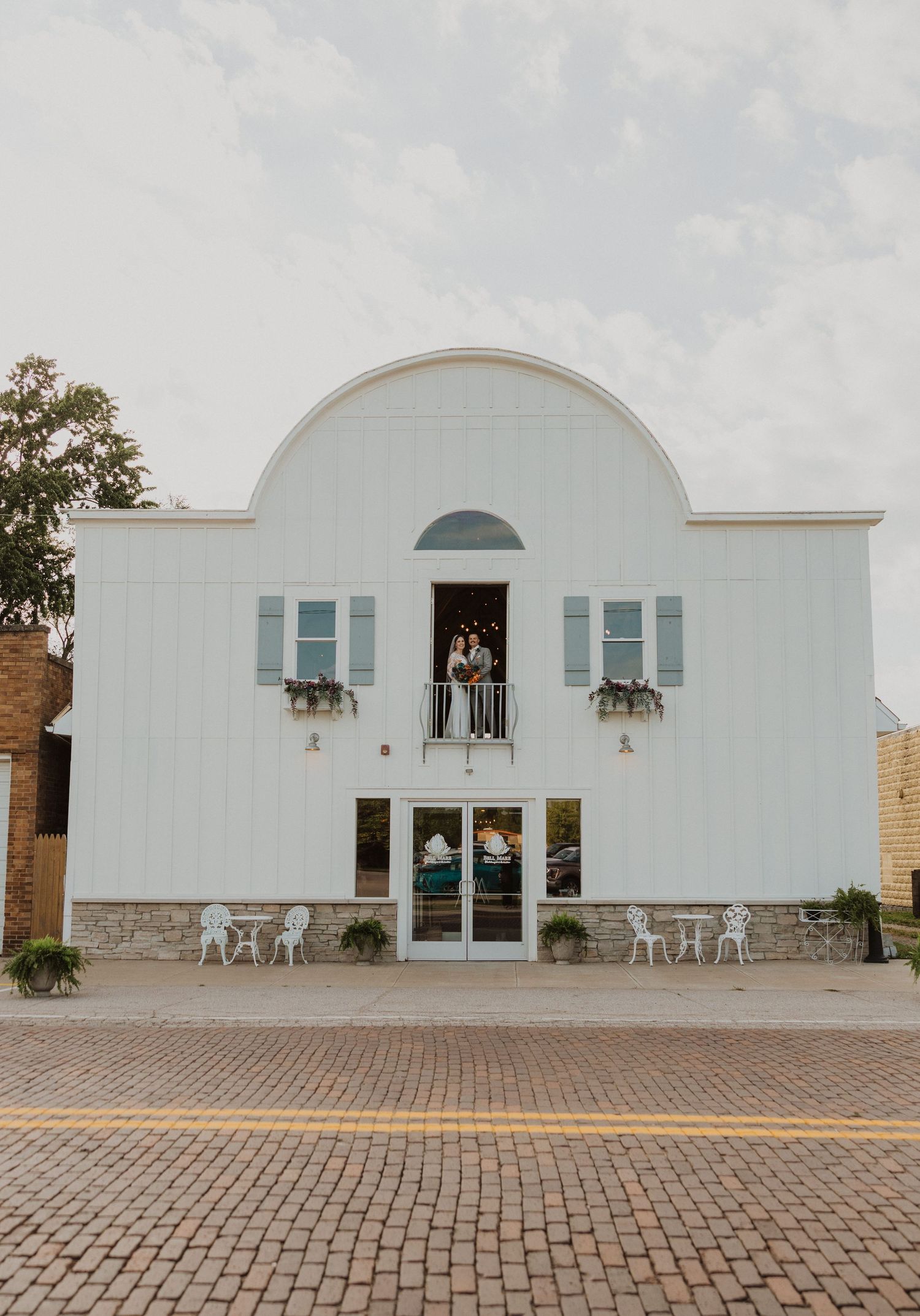Event venue with white exterior walls and brick paved entrance courtyard.