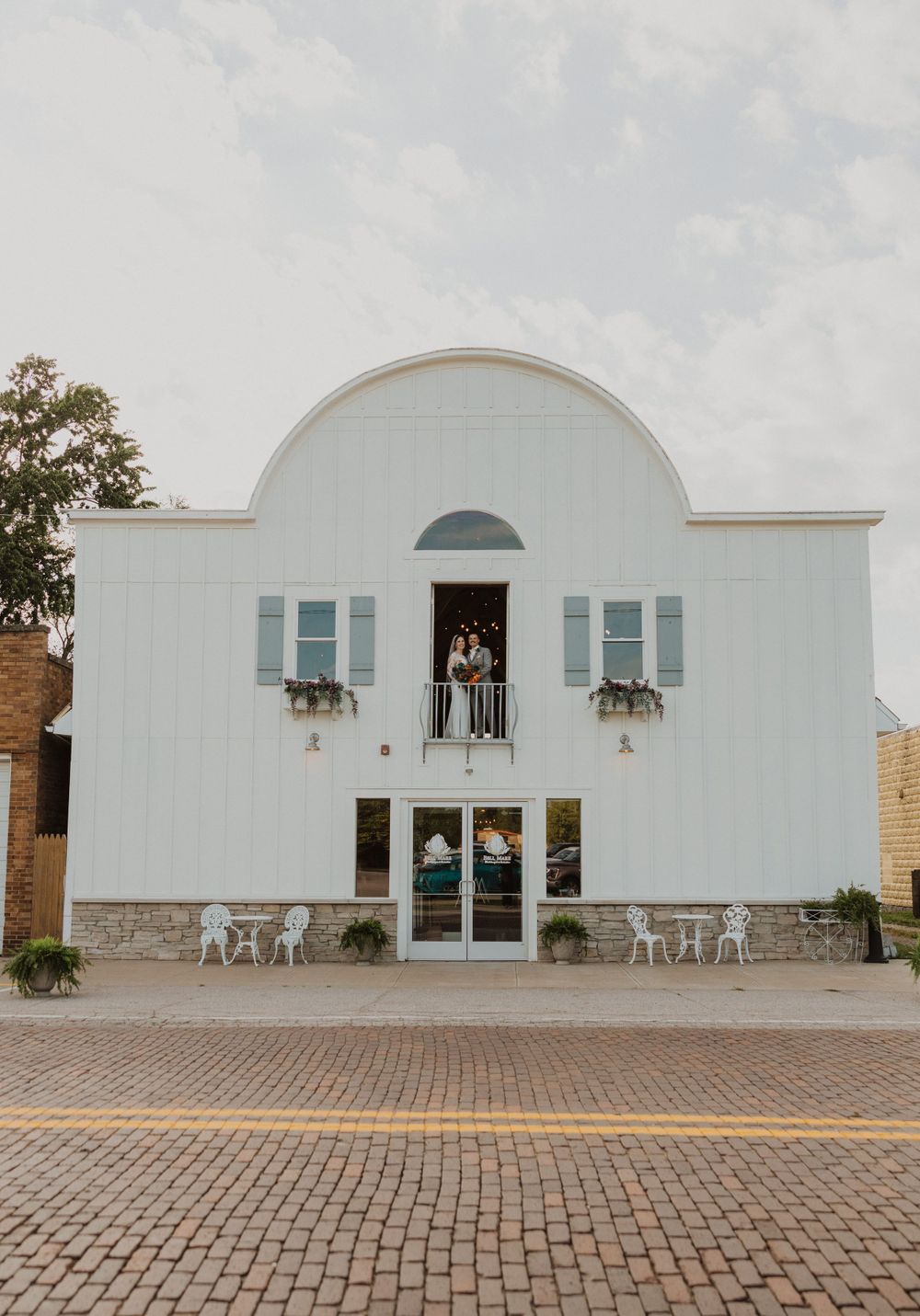Event venue with white exterior walls and brick paved entrance courtyard.