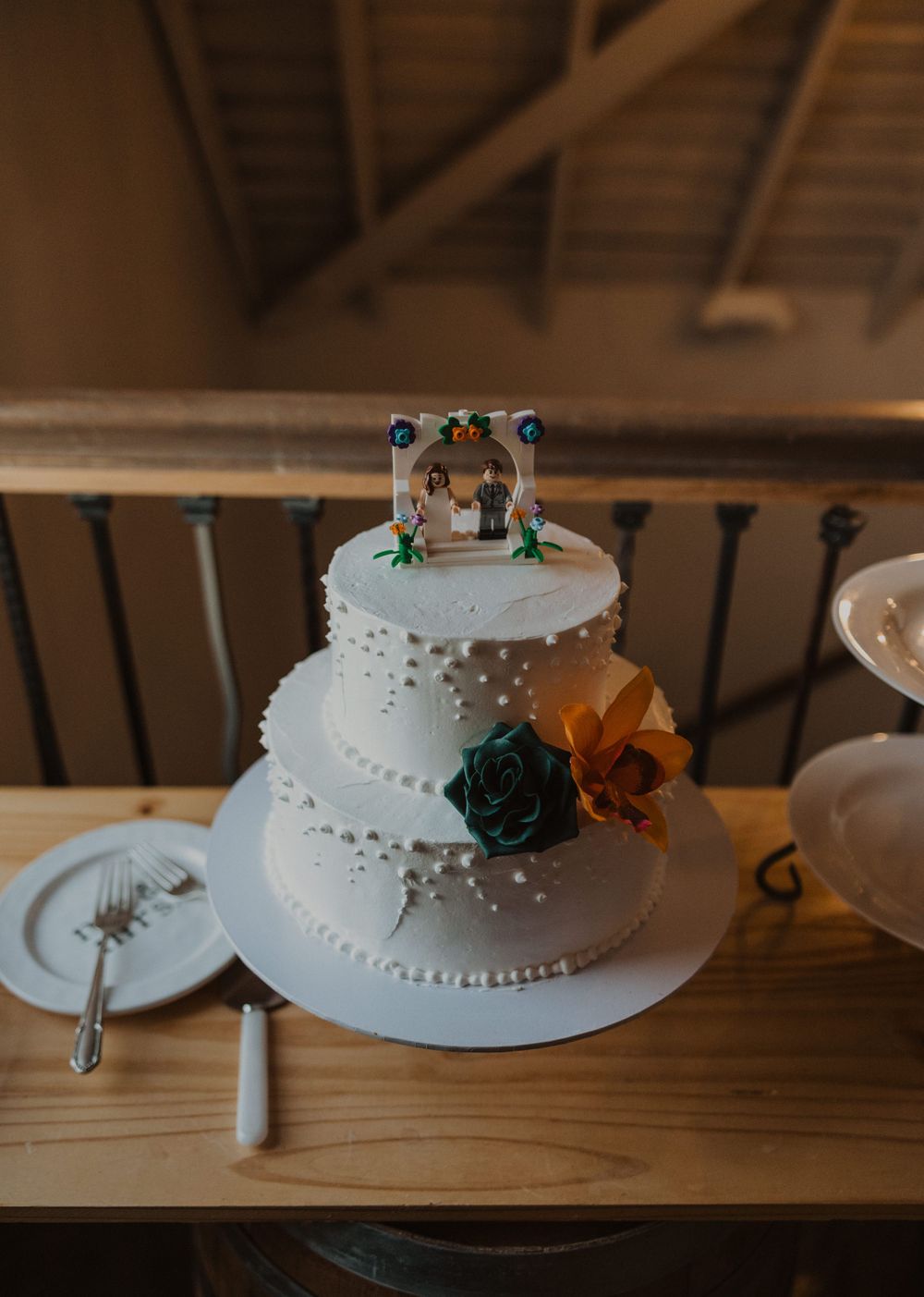 White wedding cake with delicate pearl details and floral accents displayed on a wooden surface.