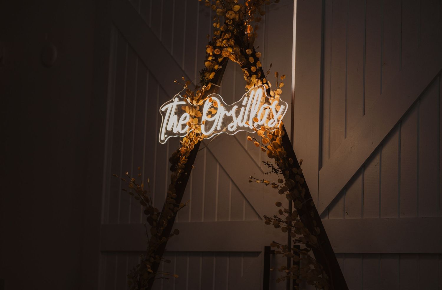 Illuminated neon sign and decorative lighting creating ambiance in a dark barn venue setting.