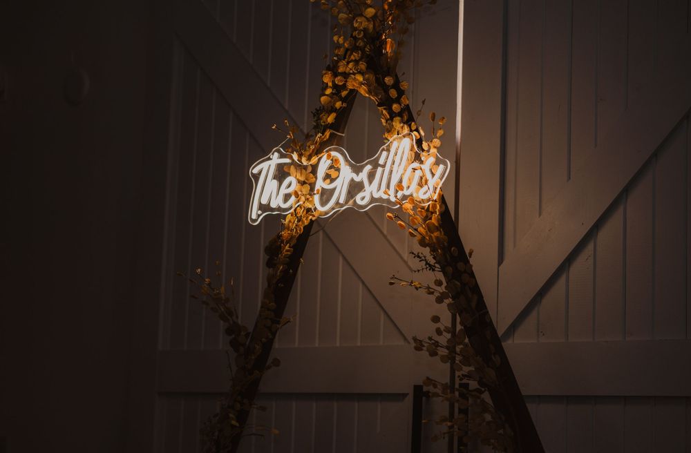 Illuminated neon sign and decorative lighting creating ambiance in a dark barn venue setting.