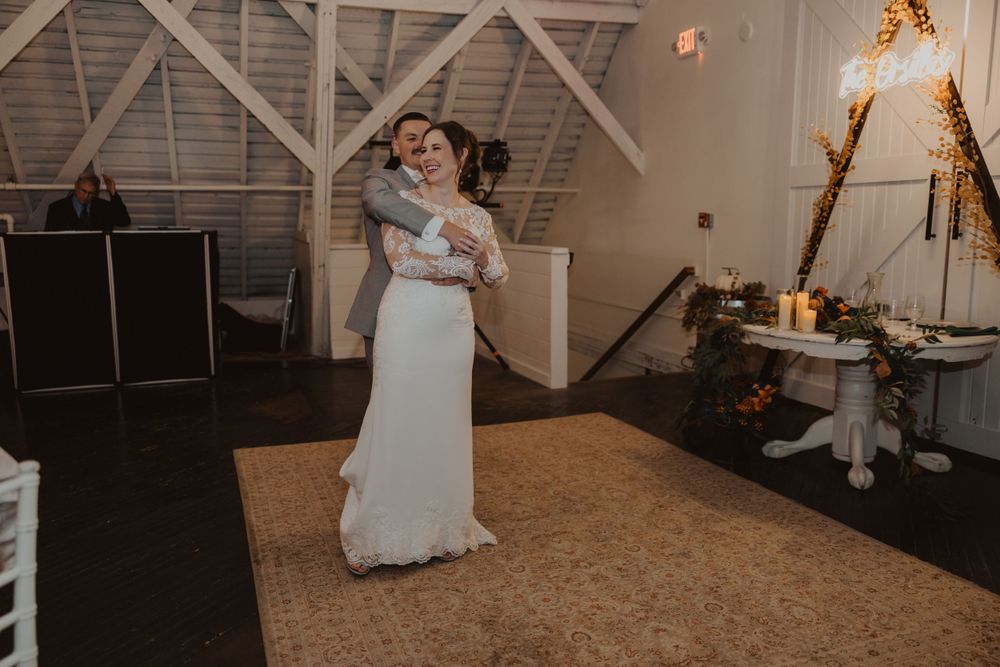 Dancers move gracefully across a wooden dance floor in an elegant barn reception space.