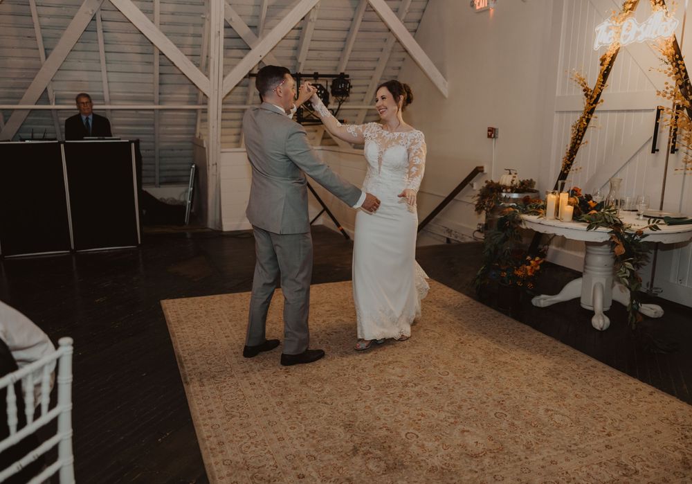 Dancers twirl across a spacious barn venue floor during an intimate wedding celebration.