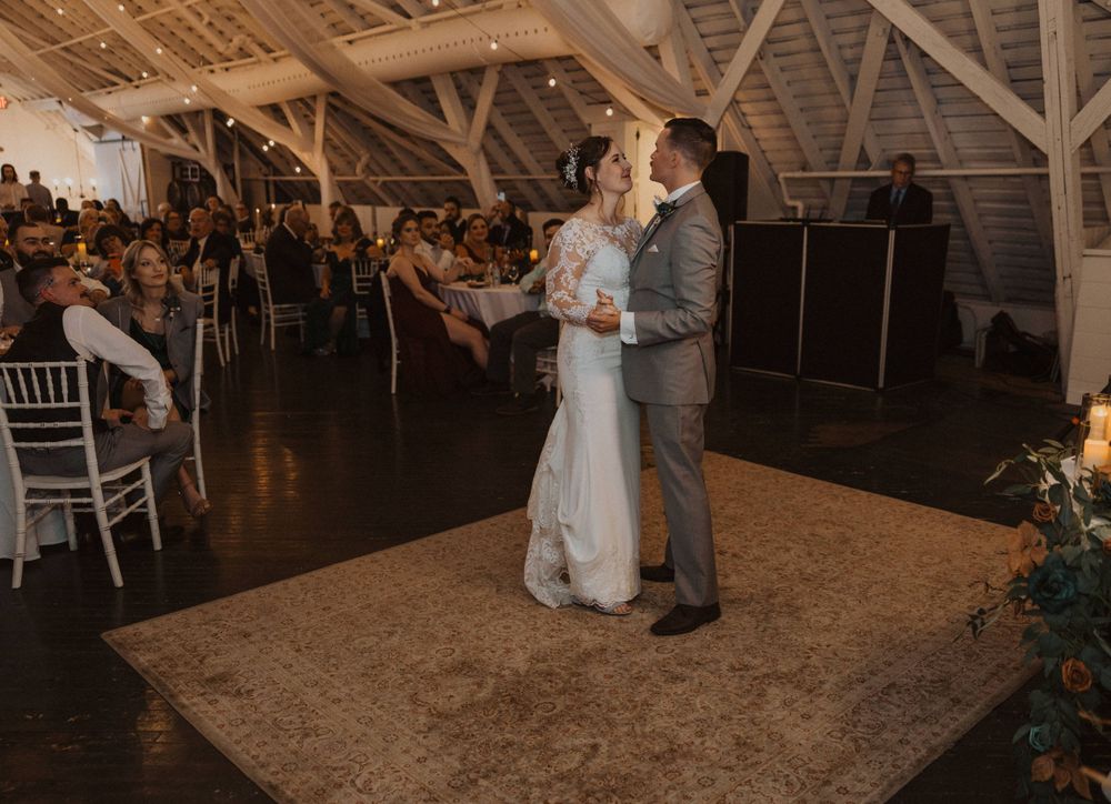 Wedding guests watch as dancers move across a beautifully lit barn reception space.