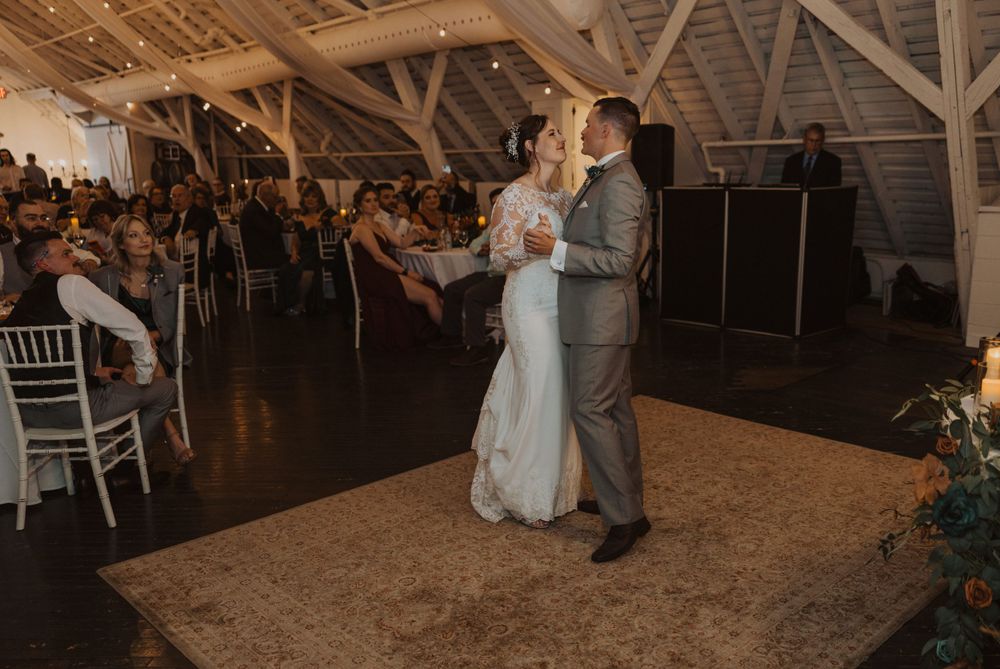 A wedding celebration unfolds on the dance floor of a charming rustic barn venue.