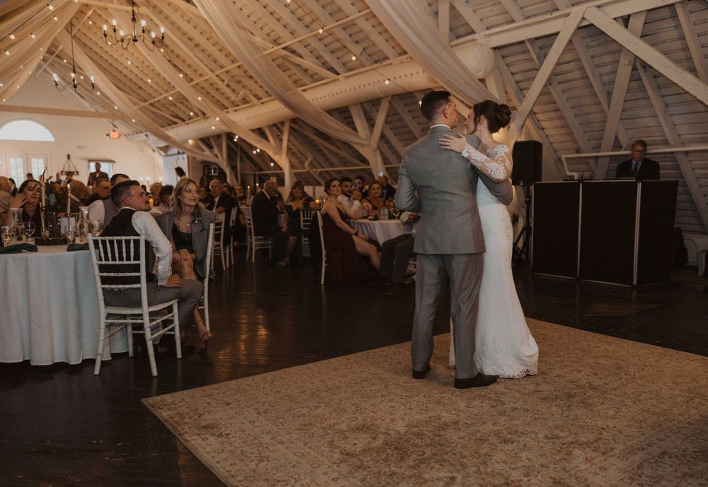 Guests observe a special dance moment in an elegantly decorated barn reception space.