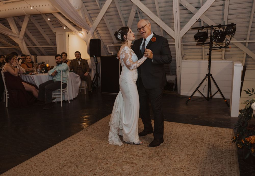 Couples dancing at an elegant wedding reception in a rustic barn-style venue.
