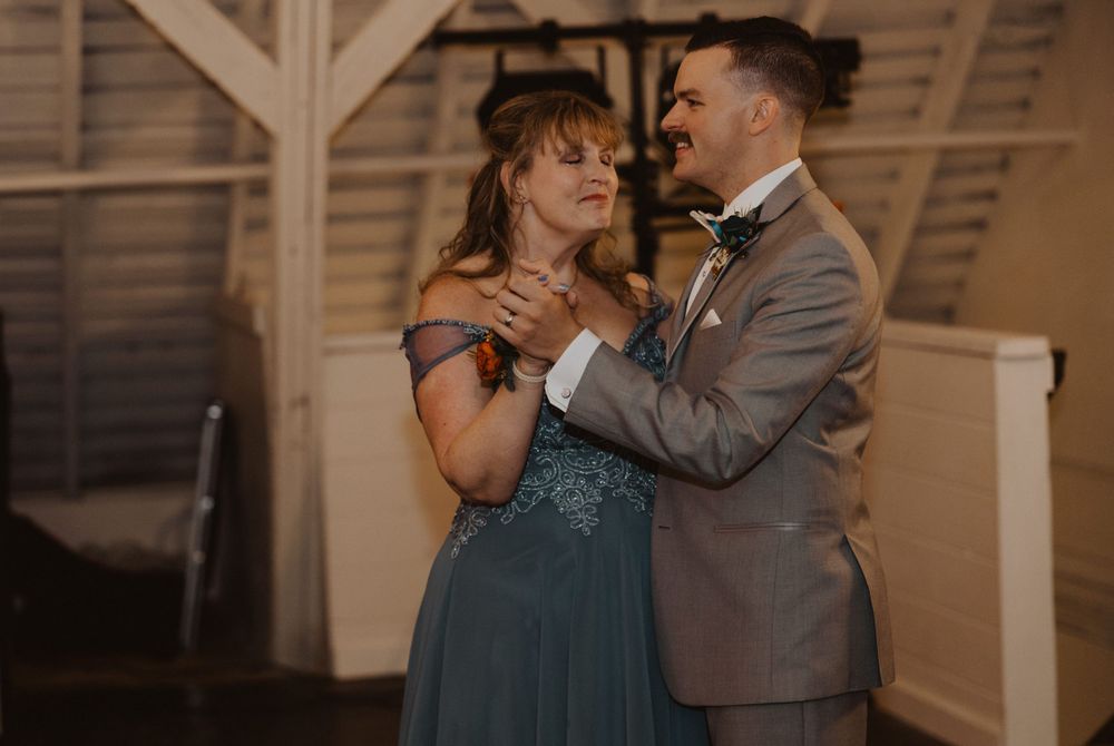 Couple dancing together in an intimate moment at an indoor wedding venue with rustic decor.
