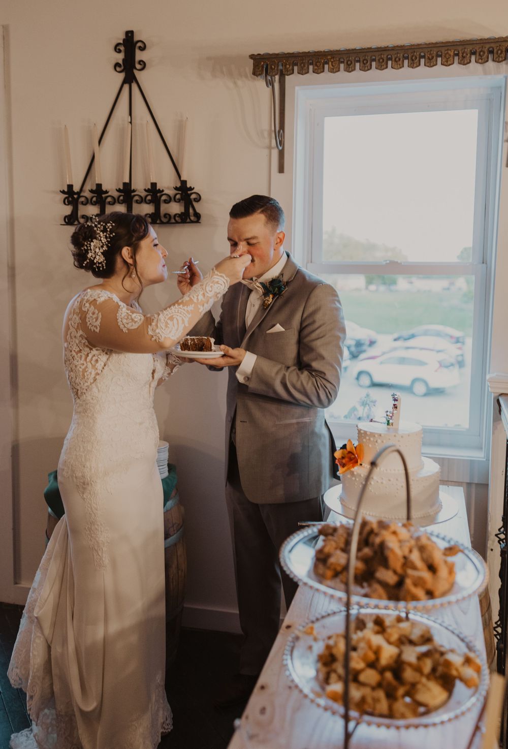 Wedding couple playfully feeds each other cake during their reception celebration.