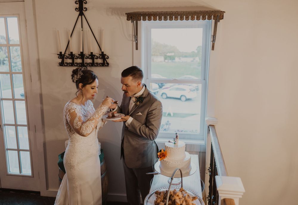 Couple enjoys a sweet moment while sharing their wedding cake at an indoor reception.