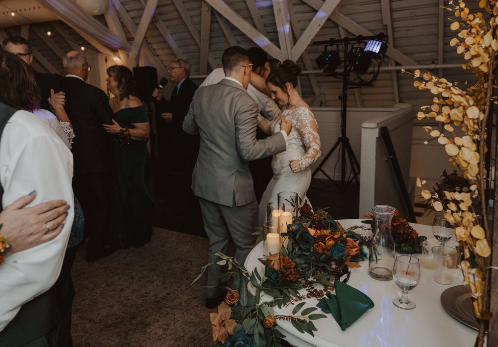 Couples dance together during an evening wedding reception with twinkle lights and rustic decor.