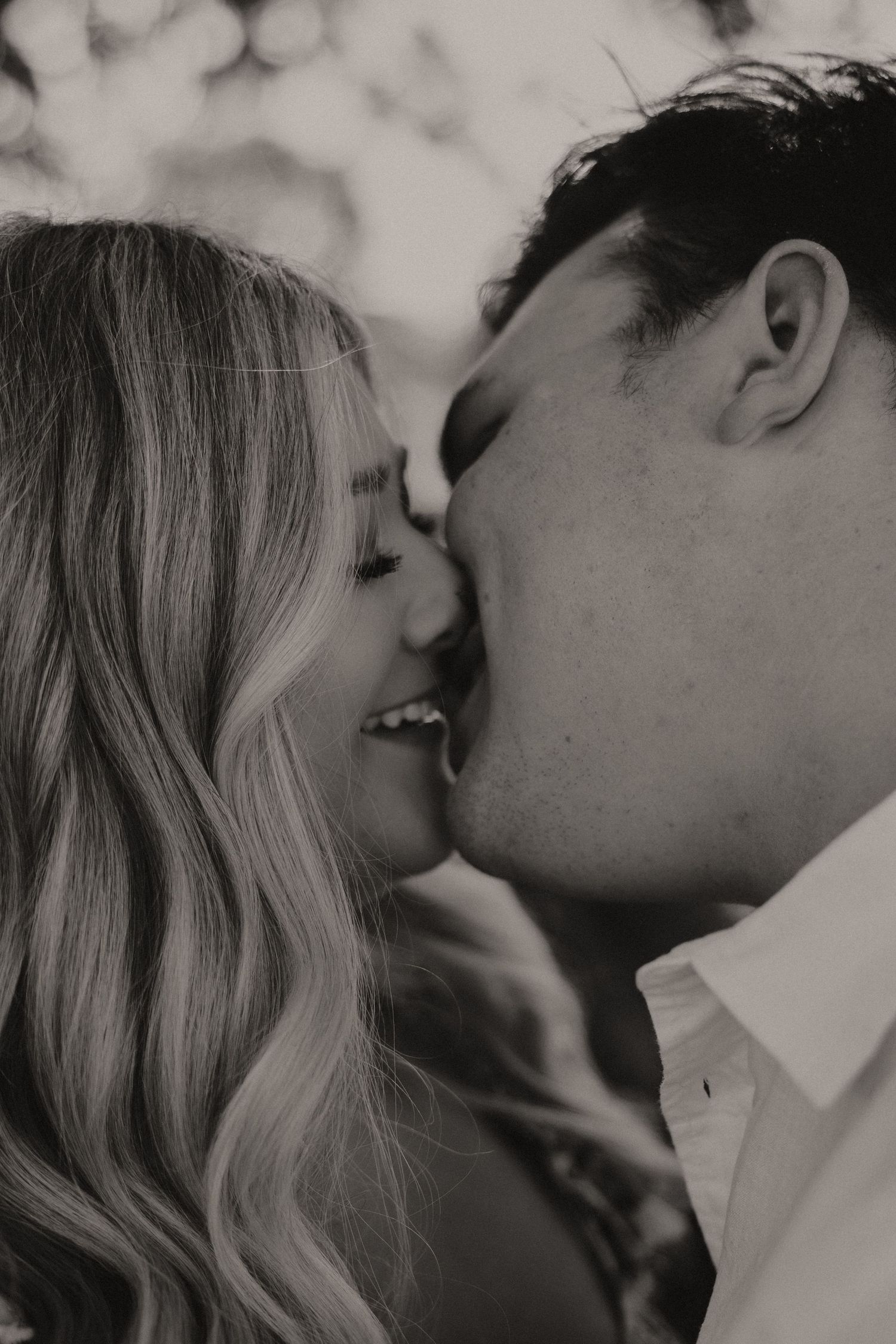 A close-up black and white photograph capturing a couple's tender kiss.