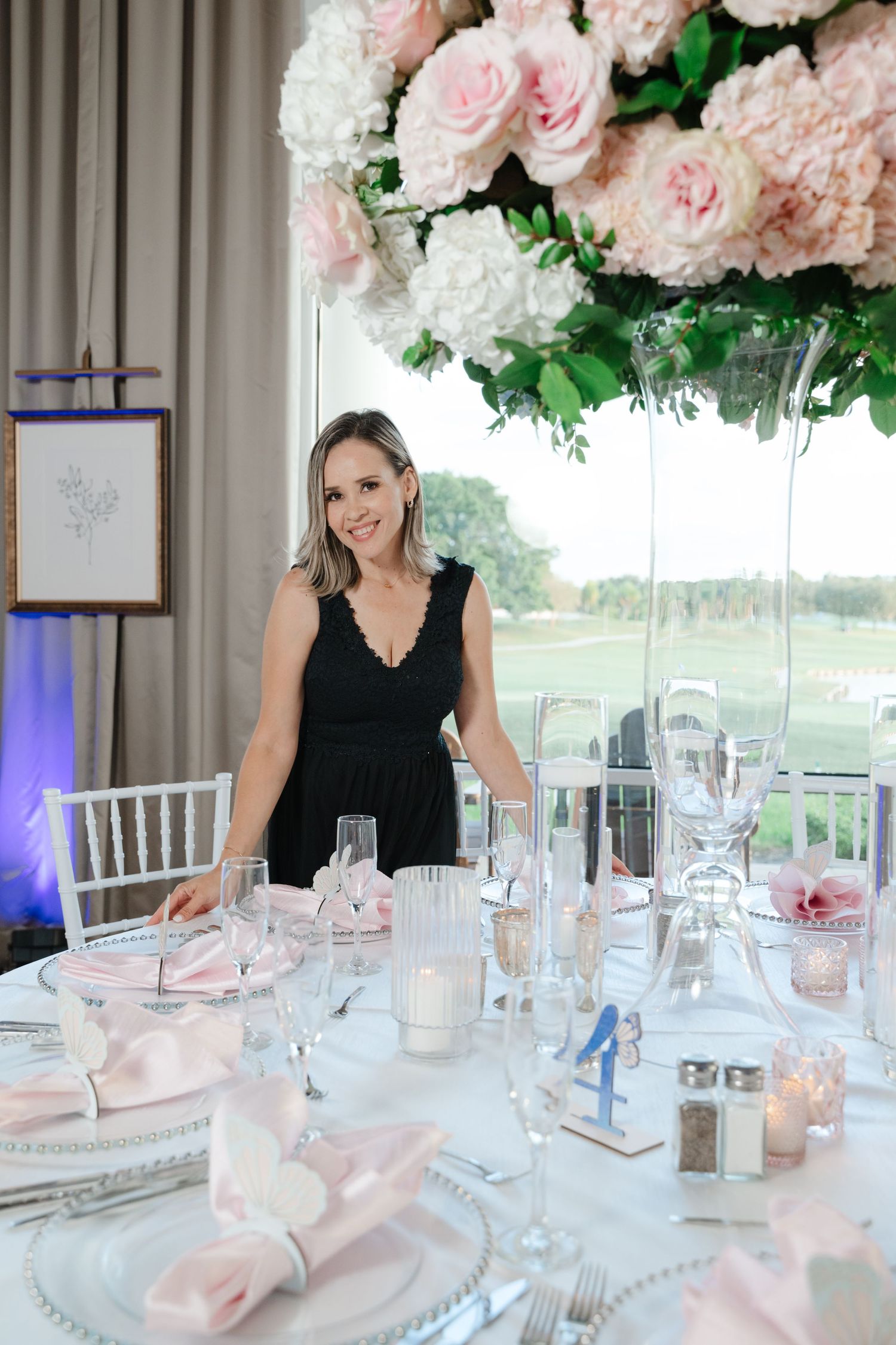 An elegant wedding reception table setting with pink floral centerpiece and formal place settings.