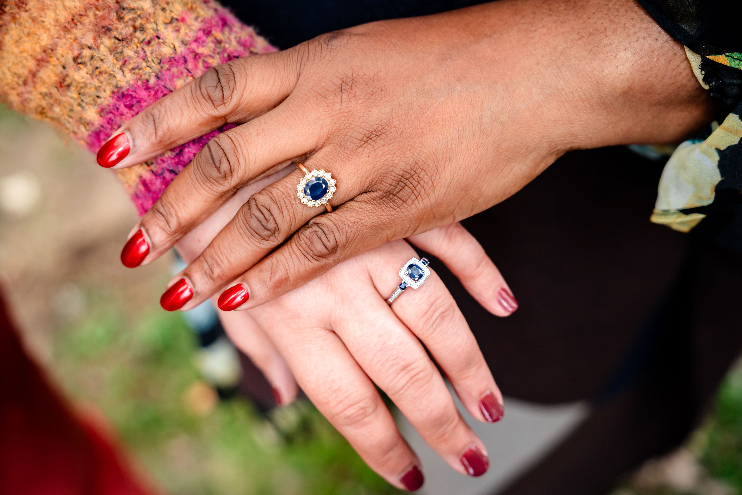 Close-up shots of hands with red nail polish and rings being displayed against a dark background.