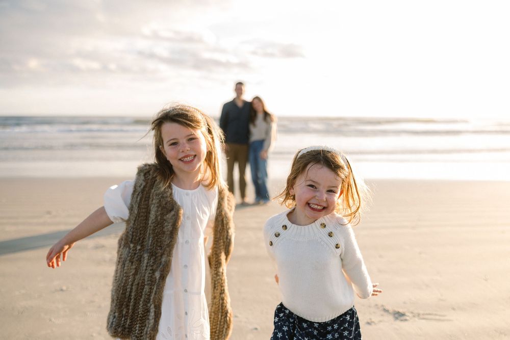 People walking together on a sandy beach at sunset with warm golden light creating a joyful atmosphere.