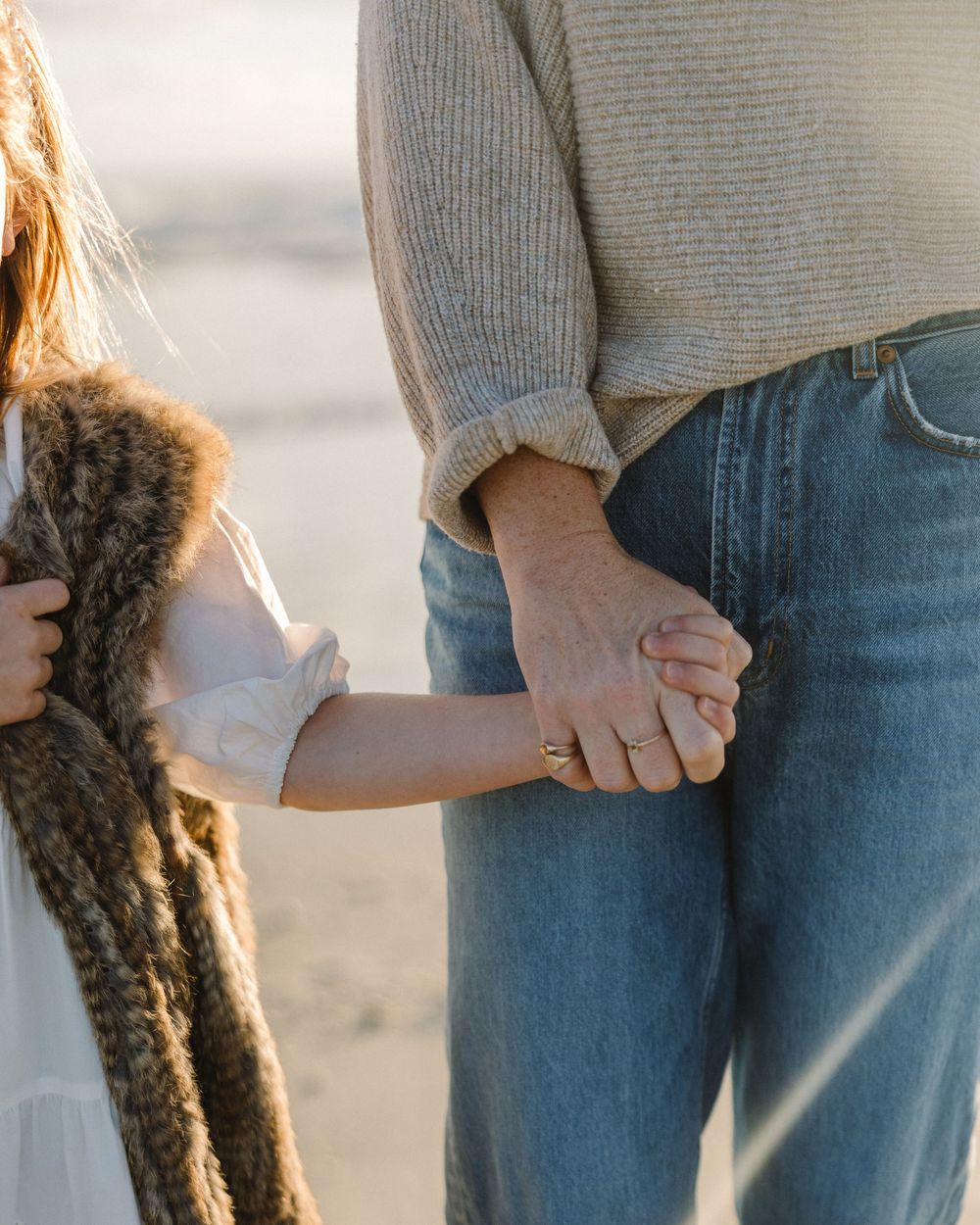 A close-up series showing hands holding and gently petting a long brown braid of hair against blue jeans.