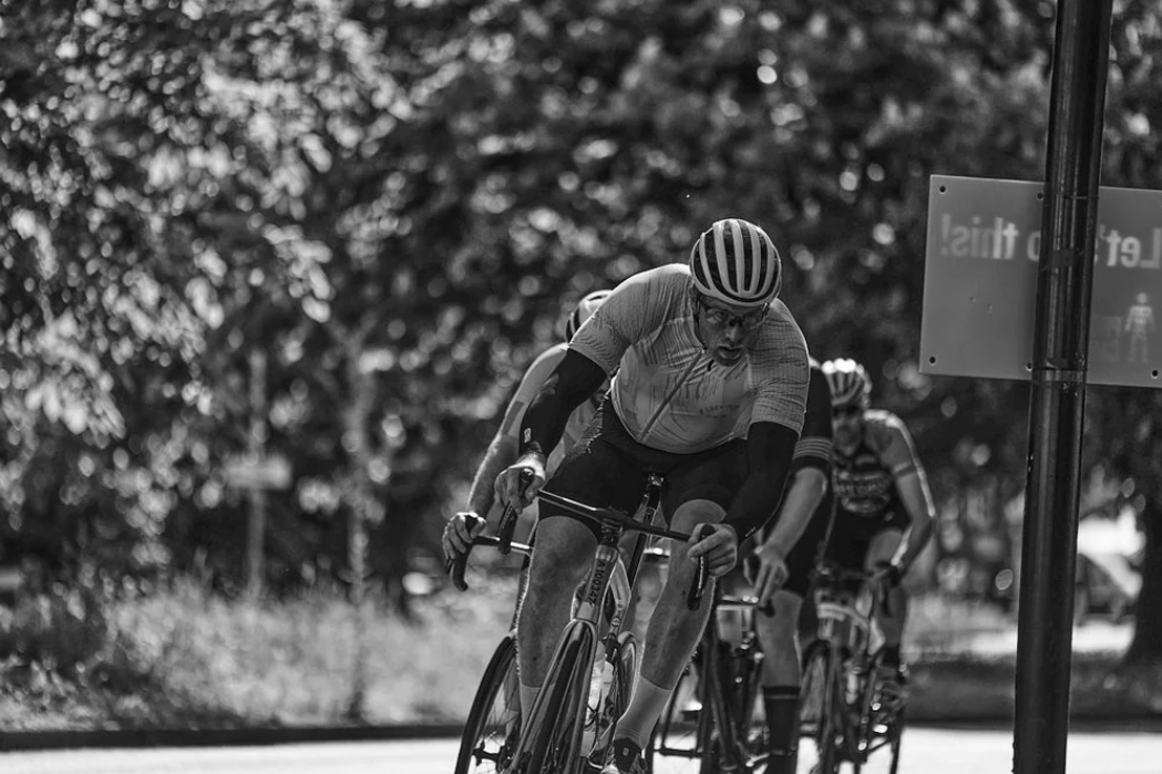 Group of cyclists in racing gear pedal through a curve during a competitive road cycling event.
