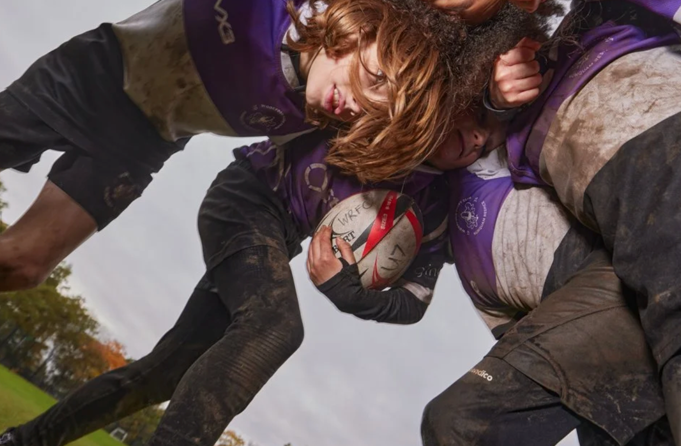 Rugby players engage in a muddy tackle during an intense match.
