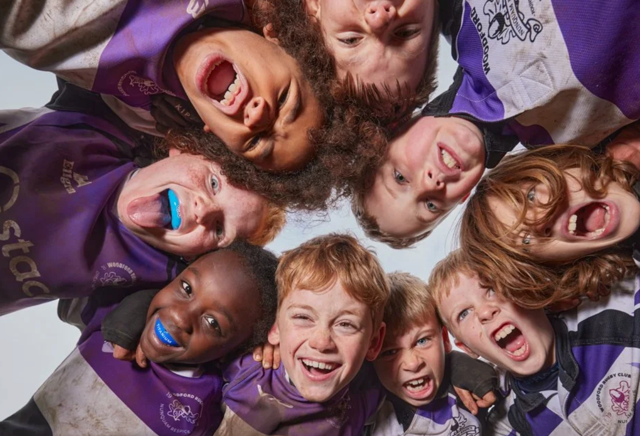 Group of athletes in purple uniforms pose together for a fun team photo.