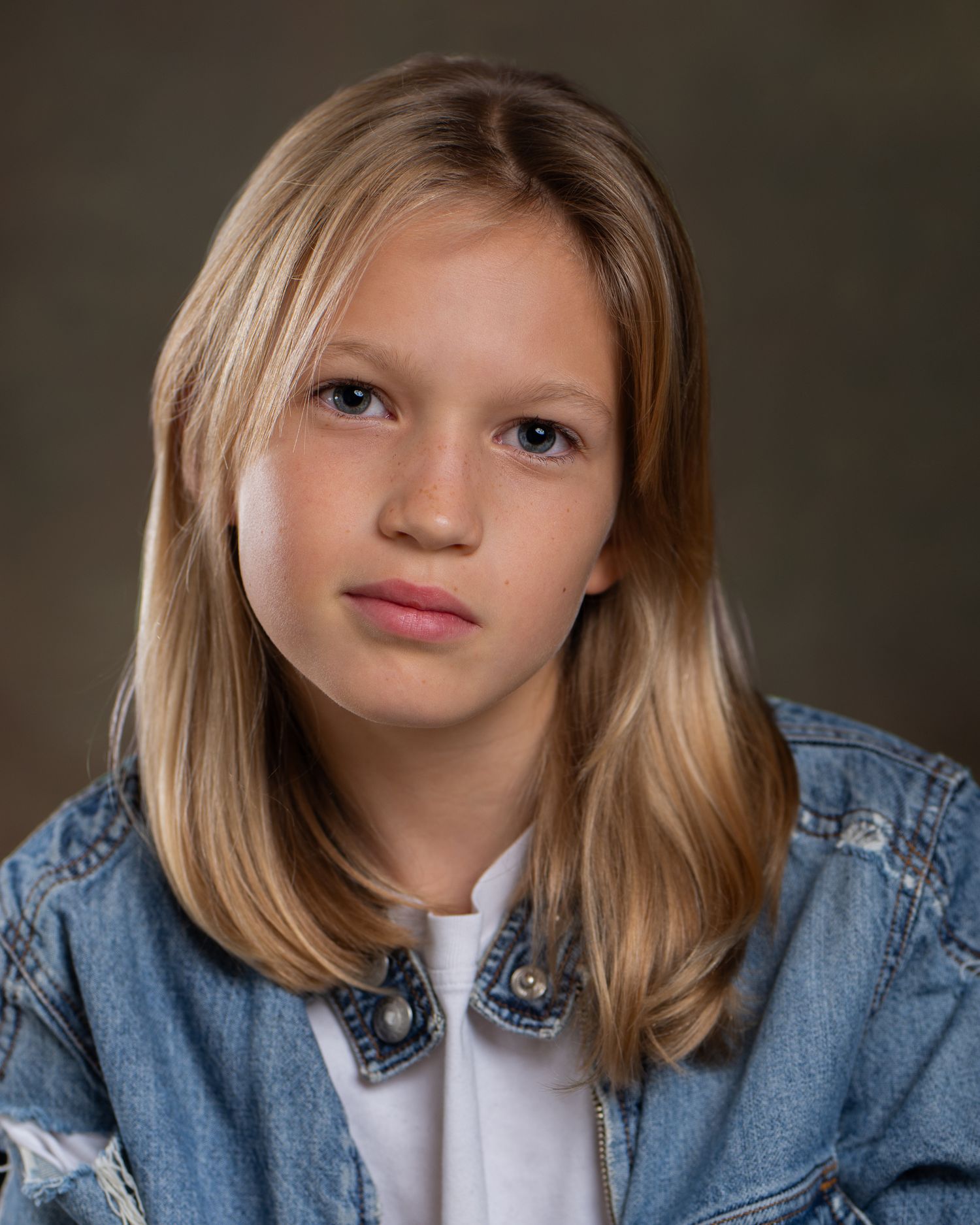 A headshot for a Spotlight portfolio showing a teenage actress in a denim jacket and white top against a dark background, Cambridge, UK