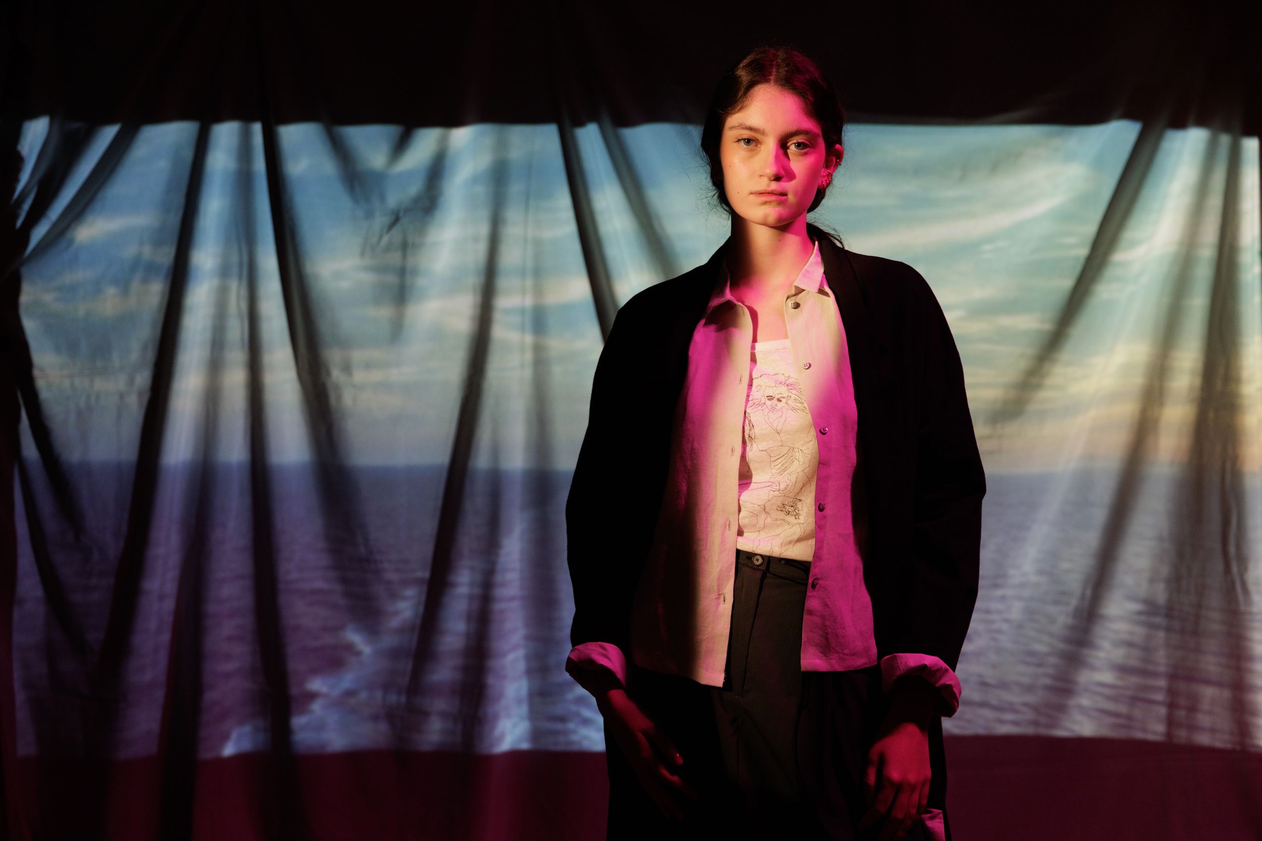 Dramatic portrait sequence with pink and blue lighting against a cloudy backdrop creating a moody atmosphere.