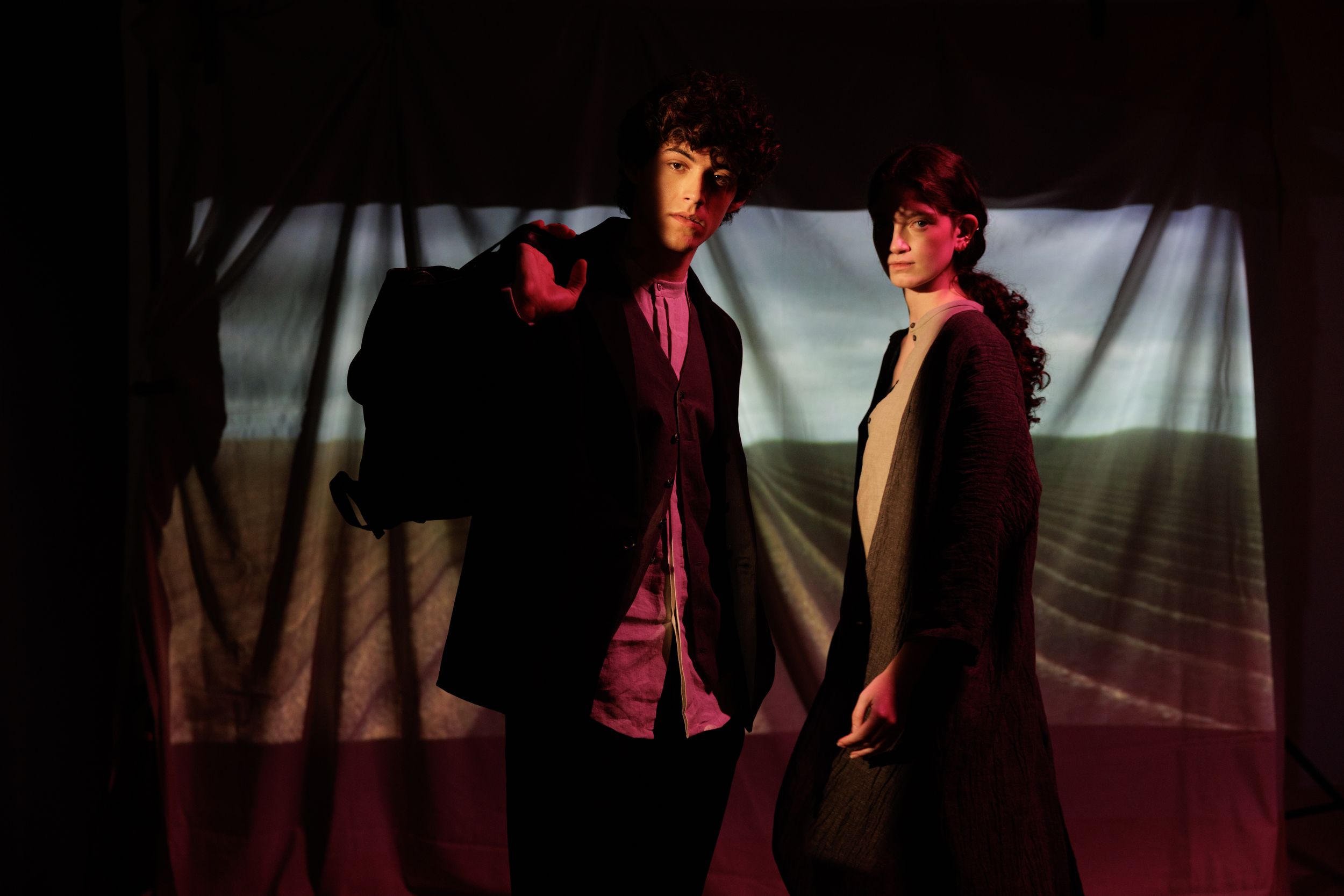 Silhouetted figures perform on a dark stage with dramatic red lighting effects.