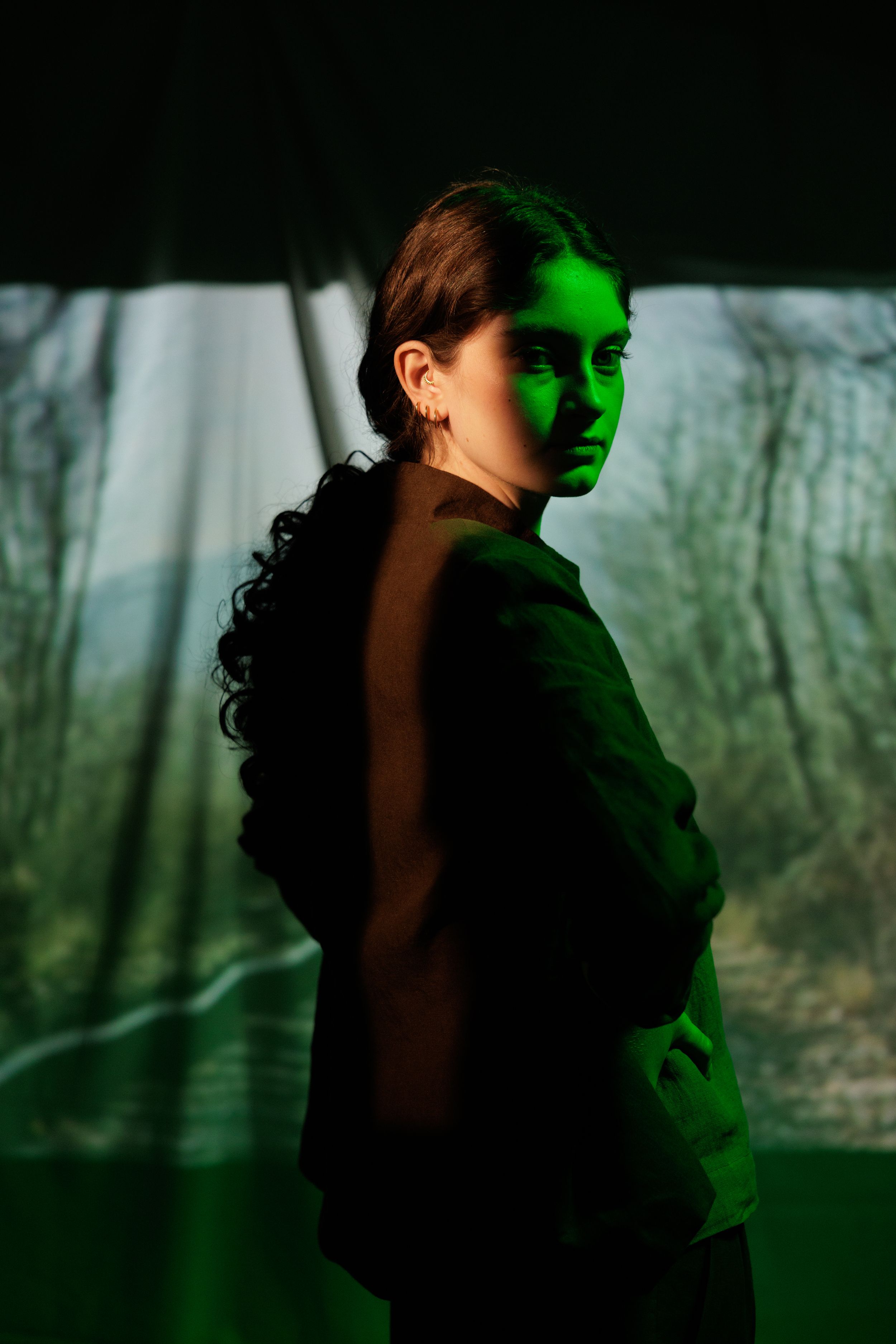 Silhouetted figure in dramatic green lighting creates mysterious mood against natural backdrop.
