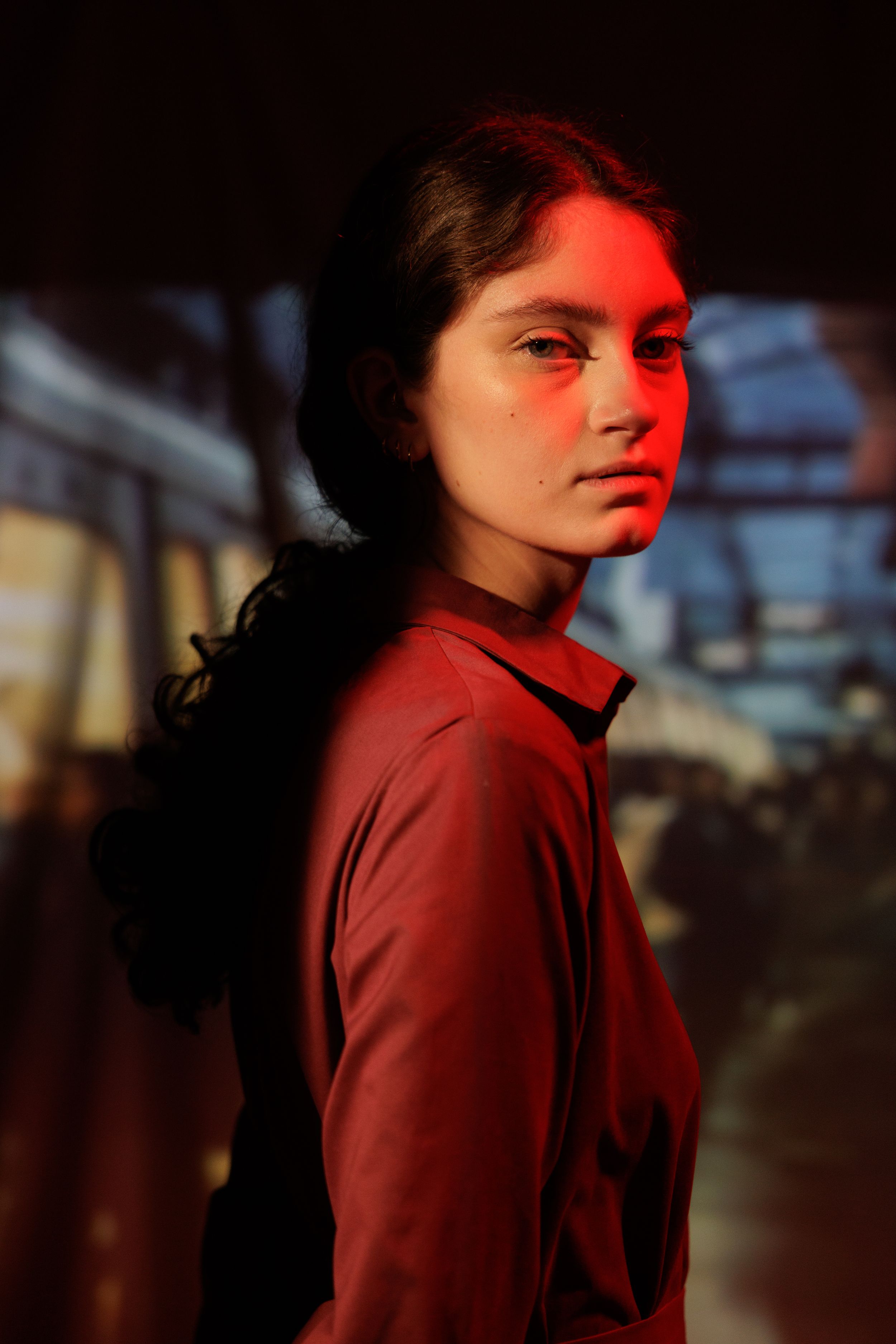 A dramatic portrait series in red lighting shows someone in a burgundy sweater turning their head against a dark background.