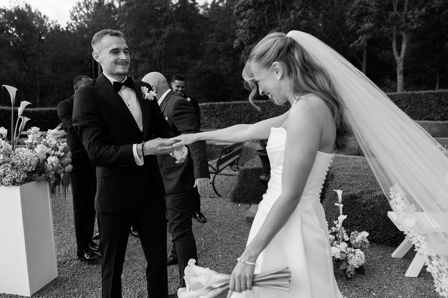 A collage of black and white wedding photos showing intimate moments between a bride and groom during an outdoor ceremony.