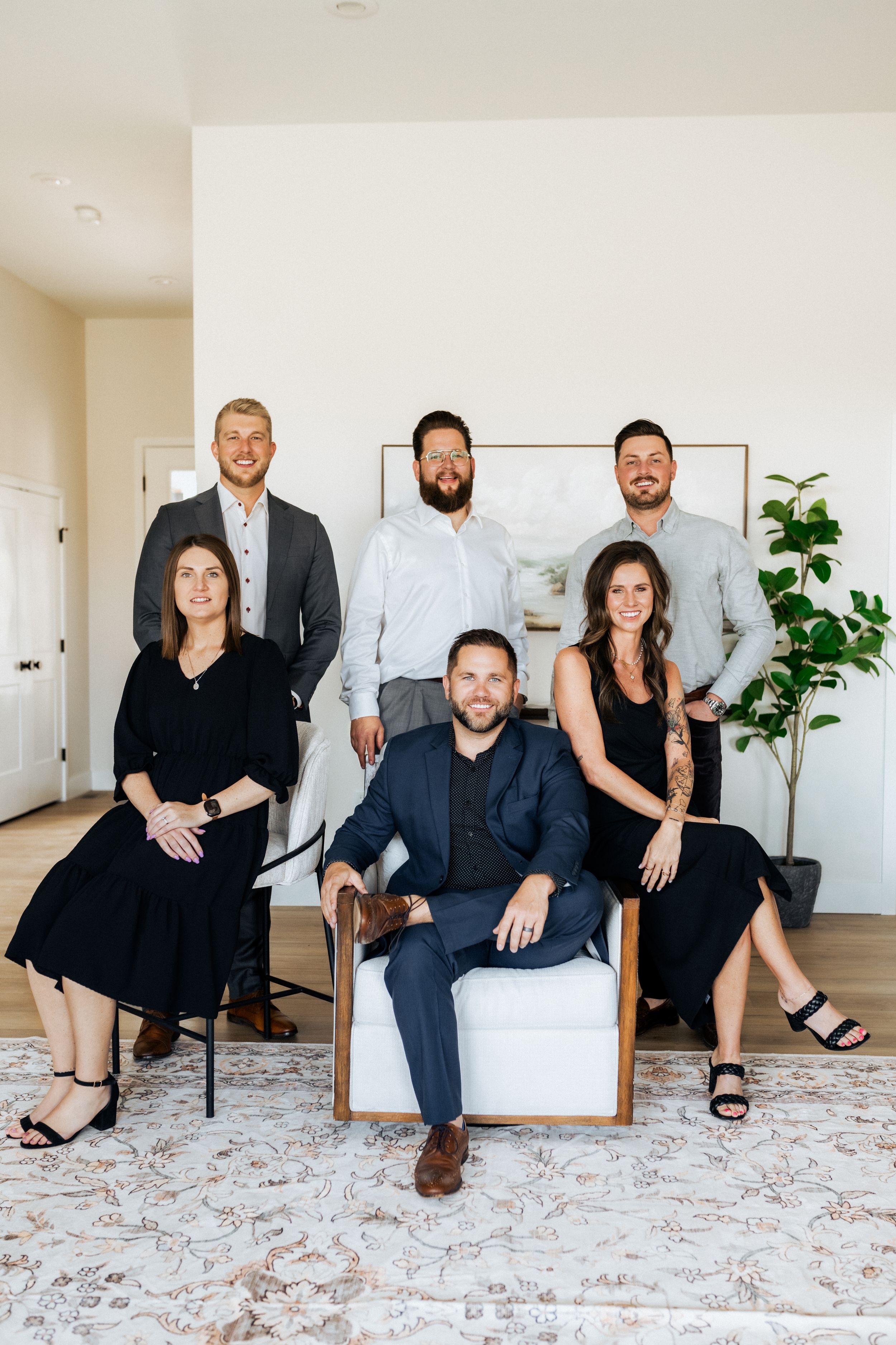 Professional real estate team of six adults posing in a modern home, dressed in business attire for a group portrait.