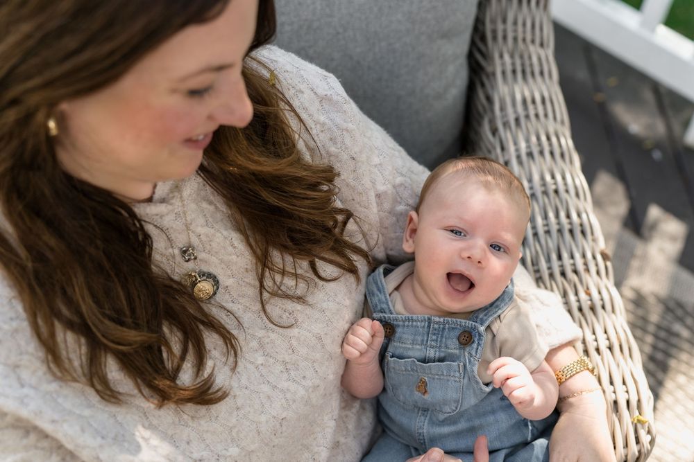A tender outdoor moment between parent and baby in denim overalls against a light background in Macedonia, Ohio in-home newborn photo pics
