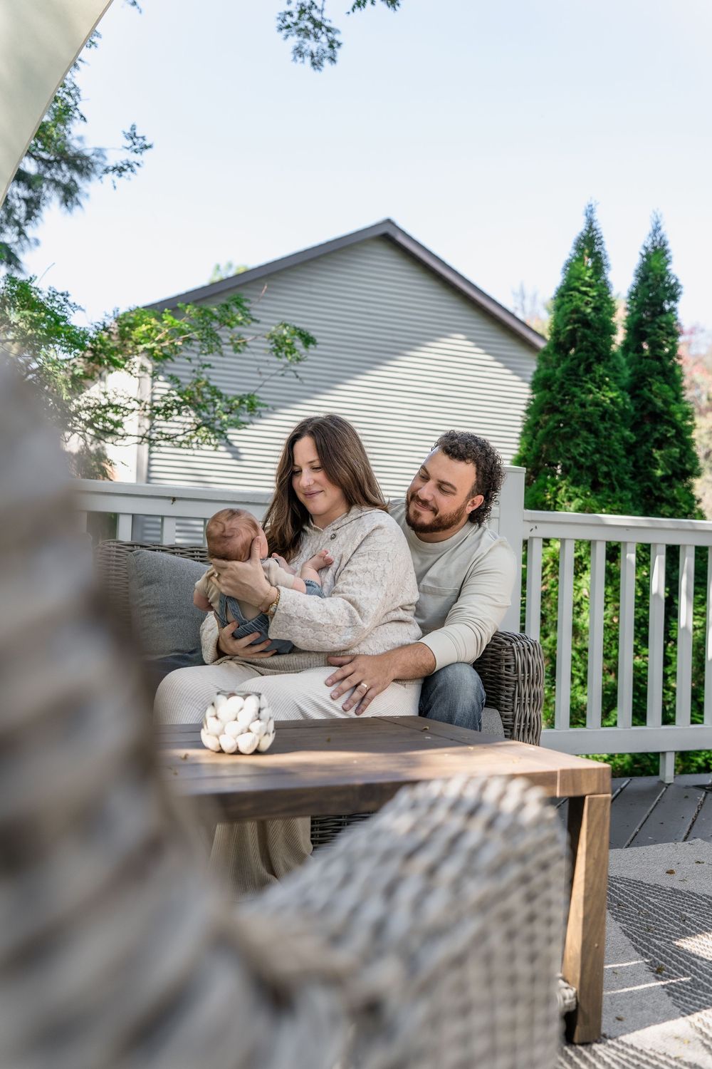 Family enjoying quality time together while sitting at wooden table on outdoor deck in Macedonia, Ohio in-home newborn photo session